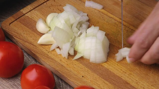 onion cut into small cubes for making sauce with a kitchen knife in hand