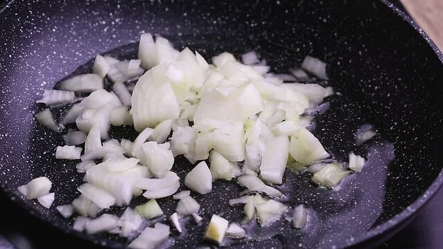 onion cut into small cubes for making sauce with a kitchen knife in hand