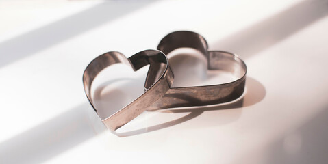 Two delicate metal sheets in the shape of hearts, concept of love, relationships and falling in love. selective focus