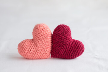 Fototapeta premium Two crocheted amigurumi pink hearts on a white background. Valentine's banner