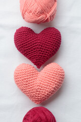 Two crocheted amigurumi pink hearts on a white background. Valentine's day