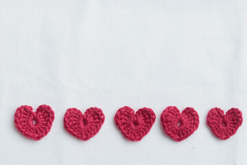 Crocheted amigurumi pink hearts on a white background. Valentine's banner top view