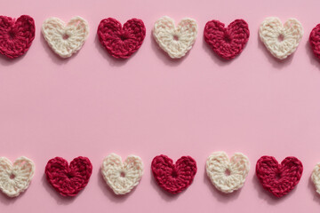 Crocheted amigurumi pink, red and white hearts on a pink background. Valentine's pattern banner