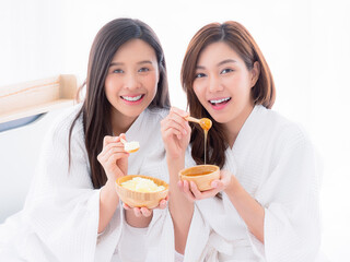 Two young women are relaxing in spa and play with skin care natural products ingredients for scrub body mask