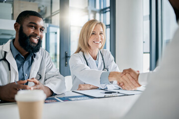 Handshake, partnership or happy doctors in a meeting after successful medical surgery or reaching healthcare goals. Teamwork, woman or black man smiles shaking hands with a worker in hospital office