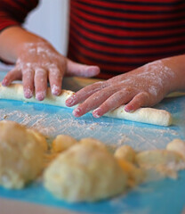 The child prepares lazy dumplings in the kitchen. Children's cooking. Board for rolling dough, flour, dough, dumplings on the table.