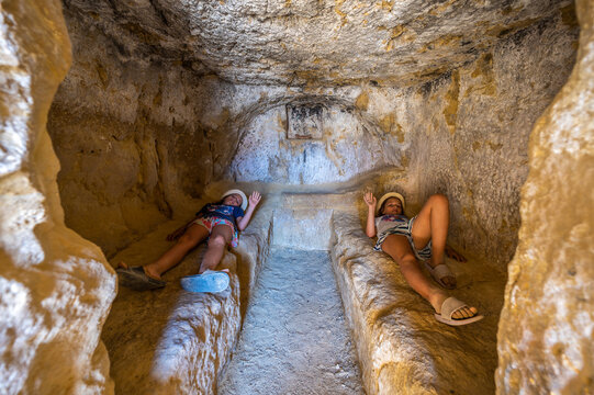 Girls in rock caves on famous Matala beach, Crete, Greece.