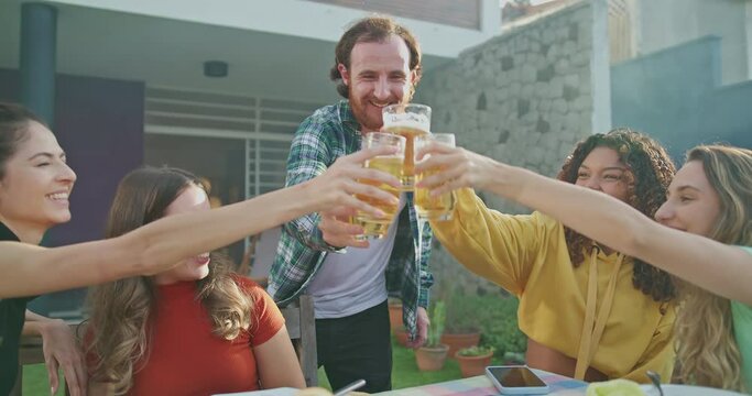 Group of diverse group of people at barbecue party together. Friends enjoying life and food together during sunny day outdoors drinking and eating.