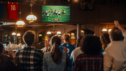 Fototapeta Group of American Football Fans Watching a Live Match Broadcast in a Sports Pub on TV. People Cheering, Supporting Their Team. Crowd Goes Ecstatic When Team Scores a Goal and Wins the Championship. obraz