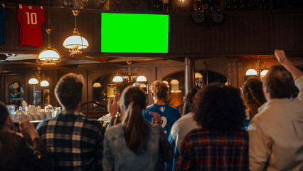 Group of Multicultural Friends Watching a Live Sports Match on TV with Green Screen Display in a Bar. Happy Fans Cheering and Shouting, Celebrating When Team Scores a Goal and Wins the Tournament. - obrazy, fototapety, plakaty