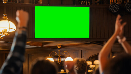 Group of Multicultural Friends Watching a Live Sports Match on TV with Green Screen Display in a Bar. Happy Fans Cheering and Shouting, Celebrating When Team Scores a Goal and Wins the Tournament.