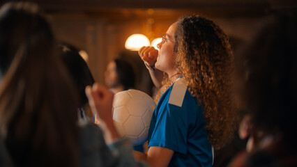 Portrait of an Excited Young Female in a Blue T-Shirt Standing in a Crowd of Sports Fans in a Bar, Watching TV Broadcast. Fans Celebrating When Team Scores a Goal and Wins the Championship.