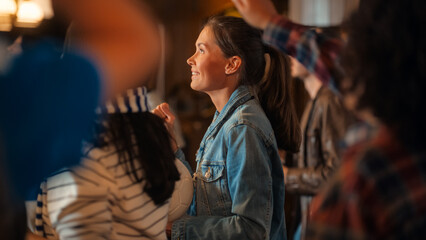 Portrait of a Beautiful Young Female in a Jeans Coat Standing in a Crowd of Sports Fans in a Bar, Watching Live Broadcast. Group of People Celebrating When Team Scores a Goal and Wins the Championship