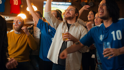 Group of Soccer Fans Watching a Live Football Match Broadcast in a Sports Pub on TV. People Cheering, Supporting Their Team. Crowd Goes Ecstatic When Team Scores a Goal and Wins the Championship.
