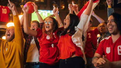 Group of Soccer Fans in Red Clothes Cheering, Screaming, Raising Hands and Jumping During a...