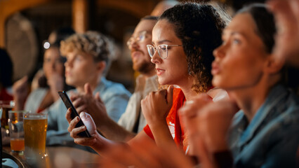 Portrait of an Anxious Multiethnic Female in Red Jersey Using a Smartphone, Nervous About the Sports Bet on Her Favorite Soccer Team. Young Woman Full of Joy When Football Team Scores a Goal.