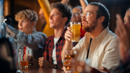 Portrait of a Happy Young Man Celebrating a Win at the Sports Pub During a Soccer Match. Looking at the TV While Sipping Beer at a Counter, Getting Emotional After Team Scores a Goal.