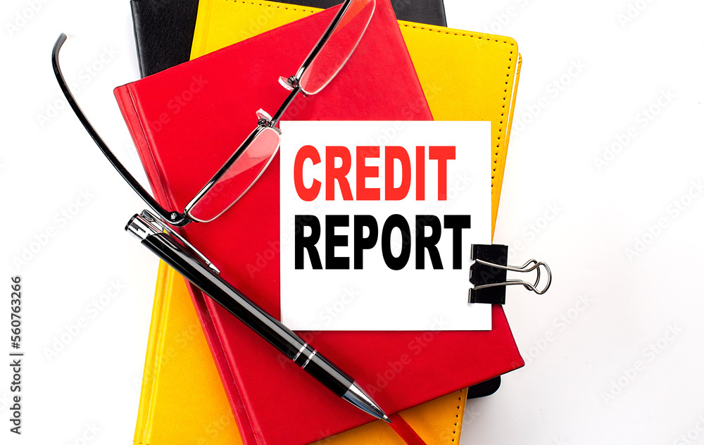 Poster credit report text written on a sticky on colorful notebooks