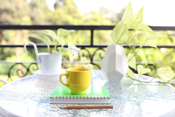yellow coffee cup and pothos neon plant on glass table
