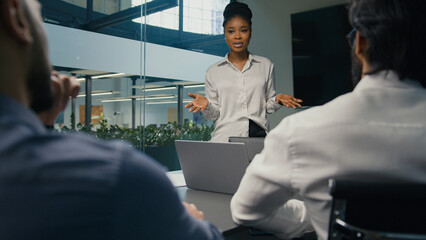 African American businesswoman mentor business coach company CEO female leader teaching business team multiracial diverse coworkers present startup project corporate training studying in office study