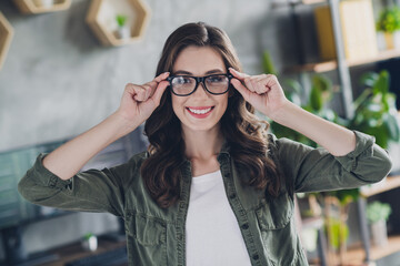 Photo of cheerful attractive intelligent person toothy smile hands touch eyewear spacious office room indoors