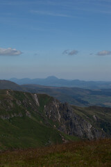 Green mid-mountain landscape under the sun without trees. View of the mountain from a peak overlooking the valley