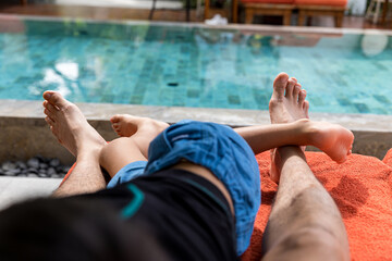 Sunbathing by the hotel tourist Hotel  swimming pool, DAD and Son legs lying down on a sunlounger...