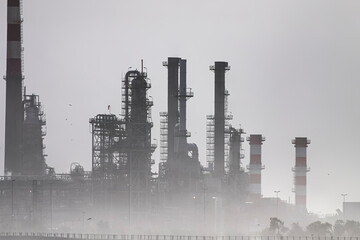 Fototapeta na wymiar Oil refinery chimneys and towers in the smog