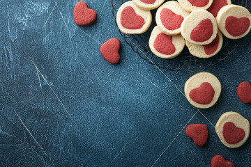 Valentines day cookies. Shortbread cookies inside a sweet red heart on parchment paper on dark blue background. Mothers day. Womans day. Sweet holidays baking. Top view.