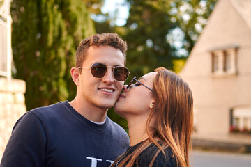 A girlfriend kissing the cheek of his boyfriend on a sunny day