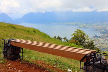 a unique wooden bench on the hill of Lawang Indonesia with views of Lake Maninjau below