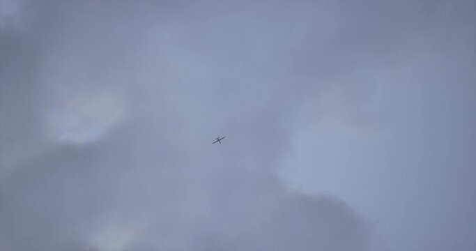 HANDHELD Witness record of a UAV military drone flying against the sky during war conflict