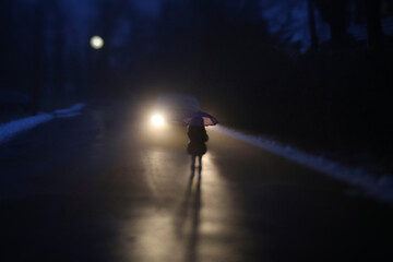Silhouette girl with umbrella standing by car on road during winter