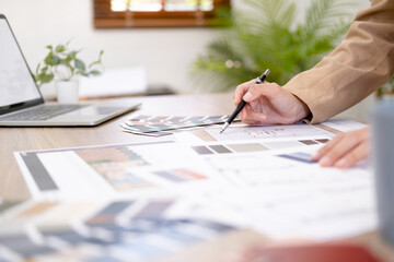 Naklejka premium Young asian female interior designer or architect working on creative project with drawing, material sample & laptop computer in office. Business of Real estate, home decoration & renovation concept.