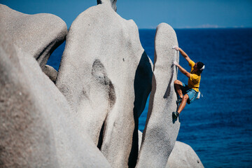 Man climbing on rock near sea, CapoÂ Testa, Sardinia, Italy