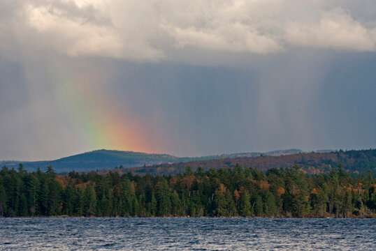 A storm in the hills beyond Richardson Lake forms a rainbow in western Maine.
