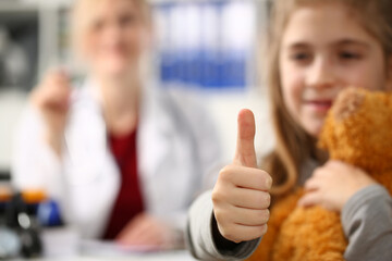 Little girl holding thumbs up in doctor office