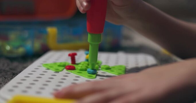 Child playing a childrens educational constructor puzzle with screwdriver