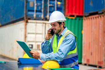 Engineer wears PPE checking container storage with cargo container background at sunset. Logistics global import or export shipping industrial concept.