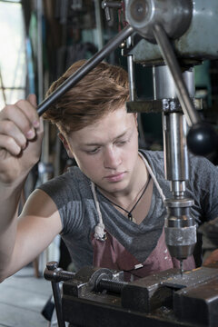 Blacksmith apprentice using drilling machine