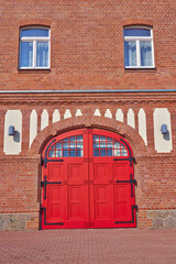 Fototapeta na wymiar An arched red door and brick wall of an old, yet fully functional fire squad station. Travel to Saxony, Germany.