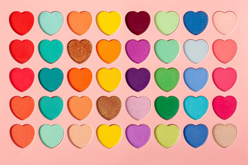 Palette of eyeshadows with multicolor heart-shaped refilles close up. Eyeshadows in macro. Cosmetic brush
