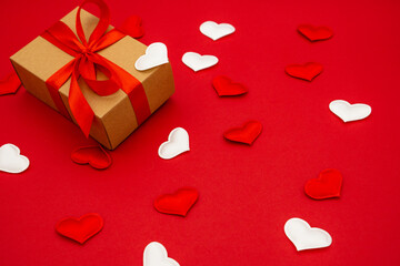 A small gift box on red background with hearts around. The concept of love