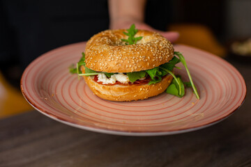 Closeup plate with juicy appetizing vegan burger isolated on wooden table background. Serving of savory hot sandwich for dinner. Fast food cafe, nutrition without meat, restaurant dish, meal