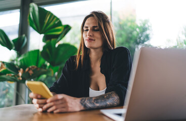 Woman sitting with smartphone and laptop in cafe