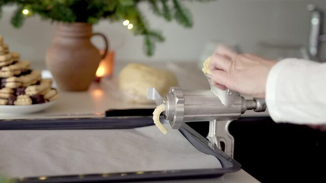 Pressing dough through a mincer or grinder to prepare homemade Christmas cookies
