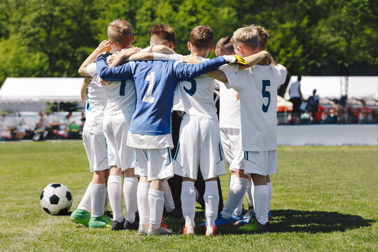 Group of teenage school boys huddling in soccer team and huddle before the final football match. Boys in soccer white uniforms