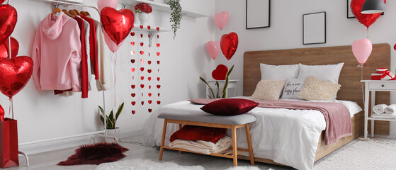 Interior of light bedroom with clothes on rack and balloons for Valentine's Day