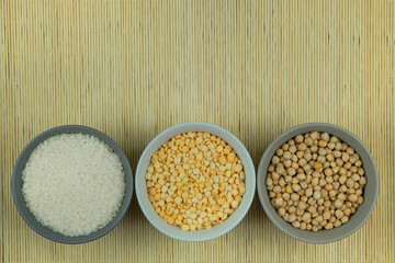 Rice, chickpeas and peas in bowls on a straw background. Vegetarian organic product. Vintage view. Top view. Copy space.