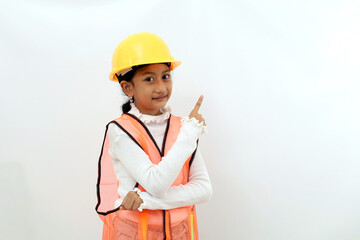 Happy Asian little girl in the construction helmet as an engineer standing while pointing sideways. Isolated on white with copyspace